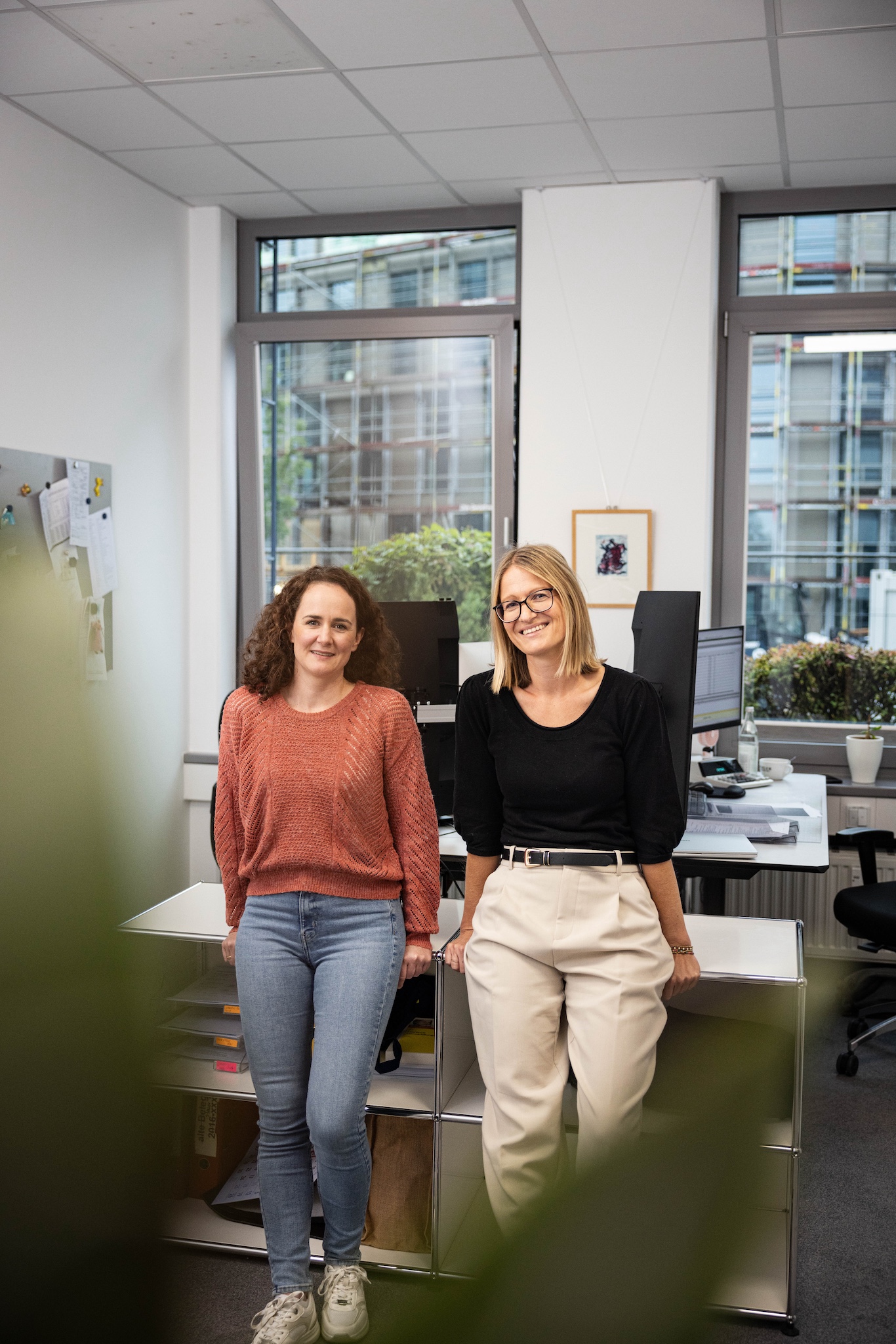 Zwei Mitarbeiterinnen stehen nebeneinander im Büro
