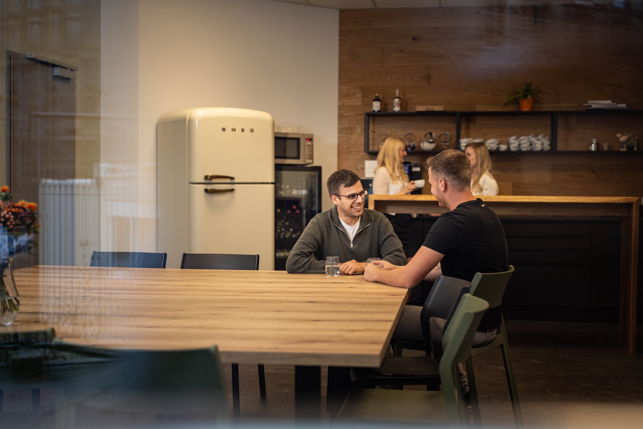 Zwei Mitarbeiter unterhalten sich in der Küche am Tisch